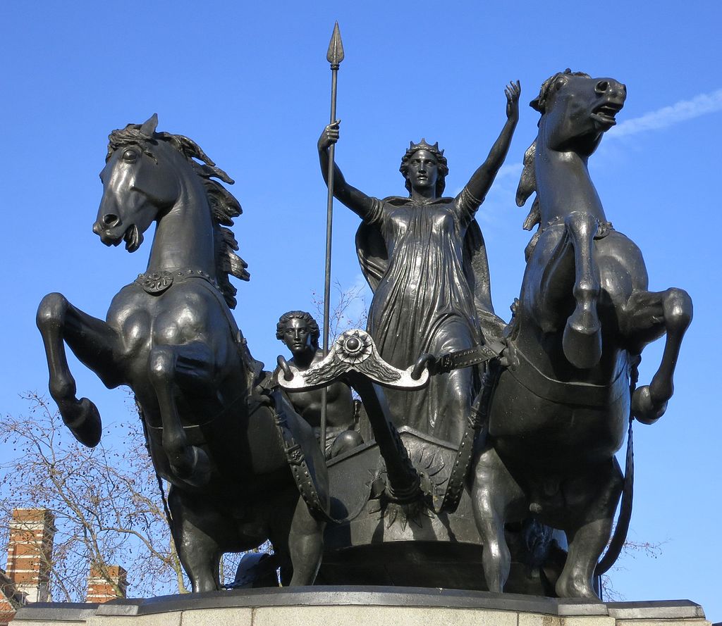 Bronze statue of Boudicca standing on a chariot pulled by two horses. Her daughters are in the chariot behind her.