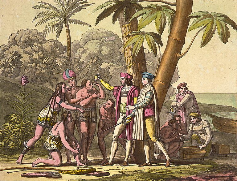 Christopher Columbus and his men wearing colourful garb hold objects up to show a group of awe-struck Native American people on the shore of a body of water.