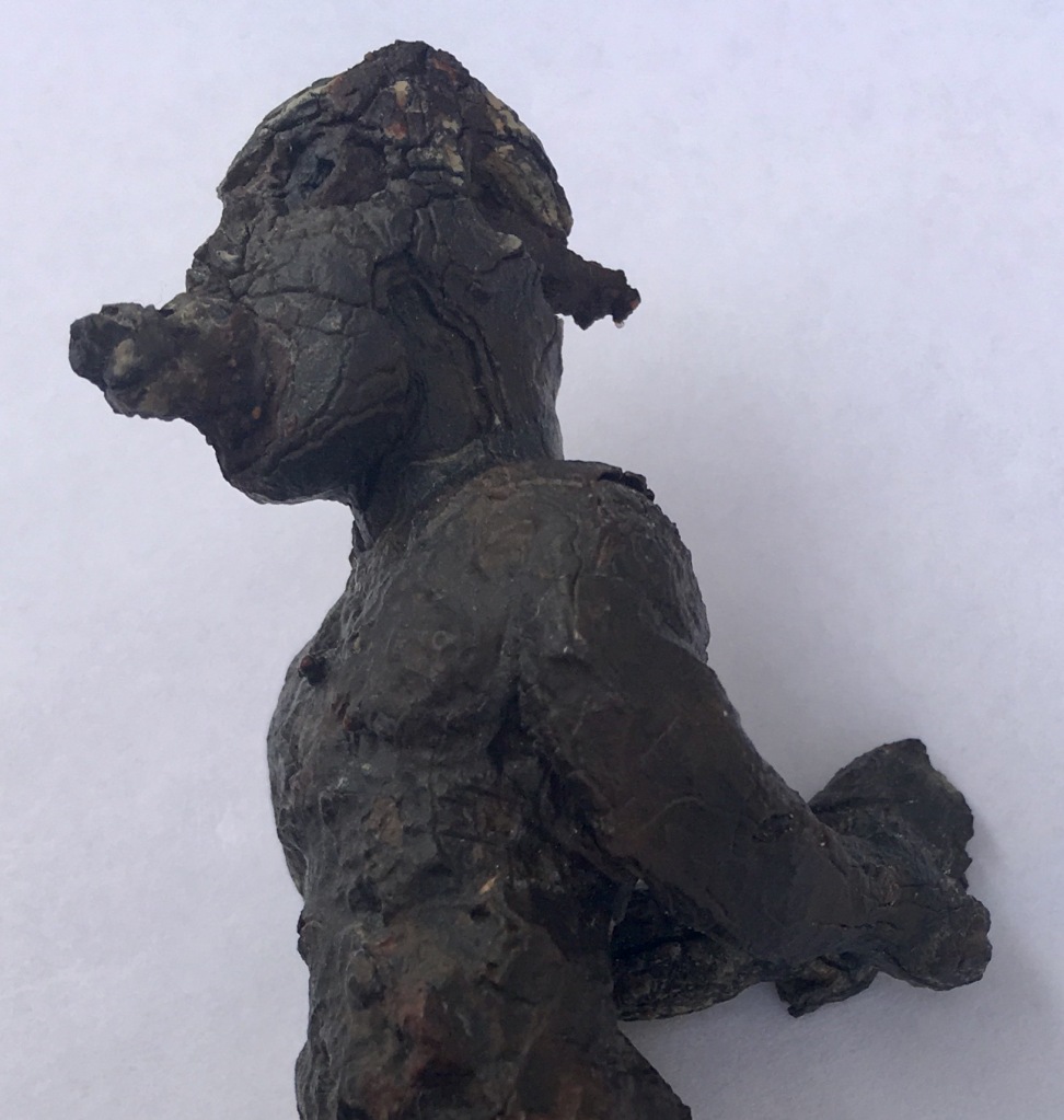 A lead effigy of a person with their arms bound behind their back.