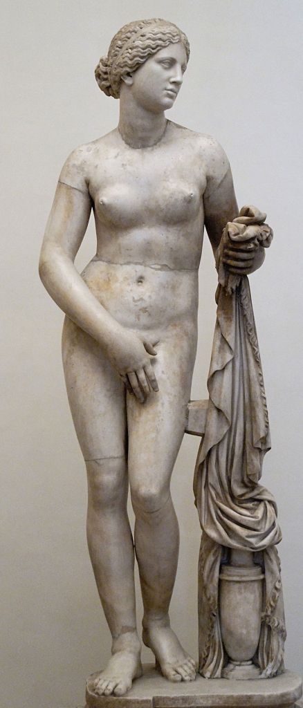 An image of a marble statue showing a naked female holding a robe in her left hand and covering herself with her right hand